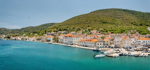 Obraz premium Croatia's island of Vis in Dalmatia. The historic town of Vis on a summer day. Mountains and forests, and the azure Adriatic Sea. Houses and church towers.