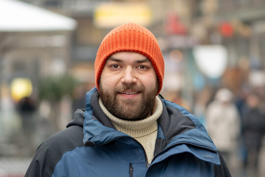 35 year old man standing in city center in winter among pedestrians.