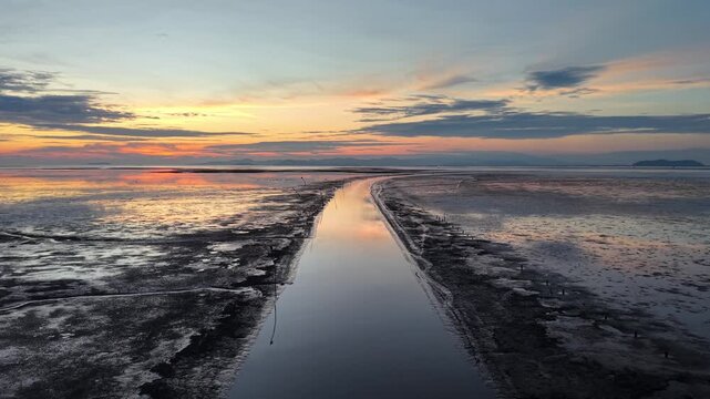 Long, narrow path runs through a wet, muddy coastal.