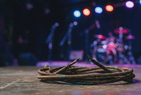 Macro photography of snapped rusted acoustic guitar string with blurred stage neon bokeh showing broken dreams