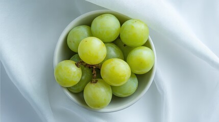 A simple arrangement of white-backed grapes in a small bowl, with their soft green color contrasting against the bright white background