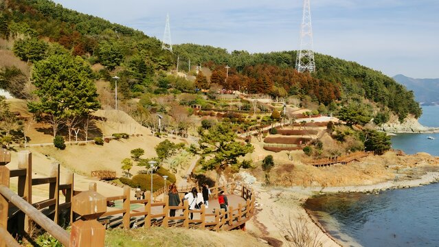 Tourists strolling along the scenic coastal wooden deck at Yi Sun-sin Park in Tongyeong.