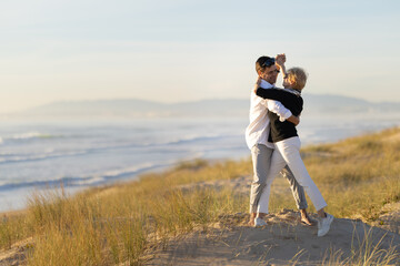 Fototapeta premium Couple dancing on sandy beach with ocean background