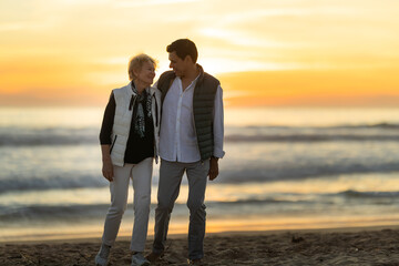 Fototapeta premium Mother and son walking on beach enjoying sunset