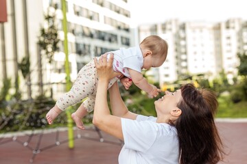 Obraz premium Mother Lifting Baby Girl at Playground