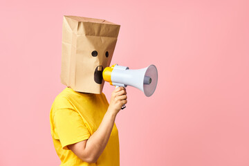 Emotional woman with paper bag on head making announcement with megaphone in hands