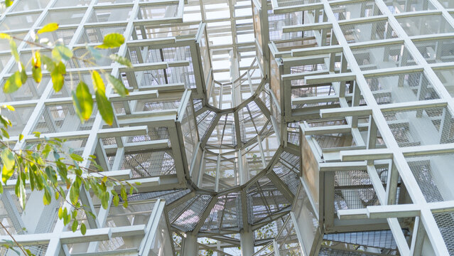 Modern architectural spiral staircase with geometric metal structure and lush green foliage