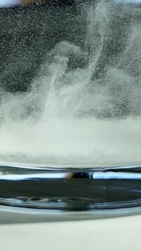 Dissolve in water. Impurities in water. Particles in water.Epsom salt. Salt. Glass. Glass of water. Epsom salt. Slow motion video. High quality FullHD footage