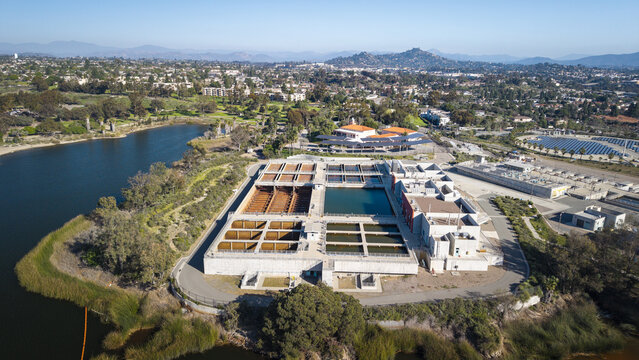 Aerial view of a water treatment facility with its stark concrete structures contrasting against the deep blue of the adjacent lake, La Mesa, California, United States.