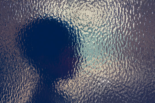 Blurred abstract silhouette of child head behind textured glass wit copy space suggesting emotion, identity, memory, perception, and mental health themes for psychology, therapy, and education uses.
