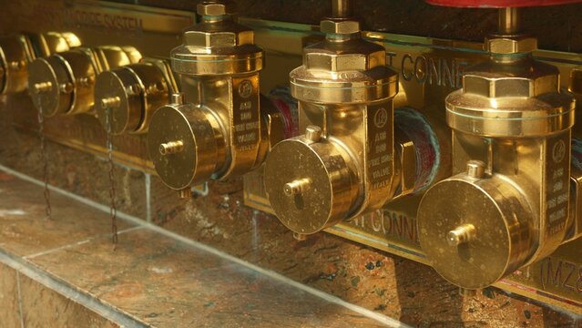 Heritage brass standpipe exterior detail, architectural conservation of brass fittings on historic building facade, exterior view of aged brass standpipe fittings with stone surround on heritage