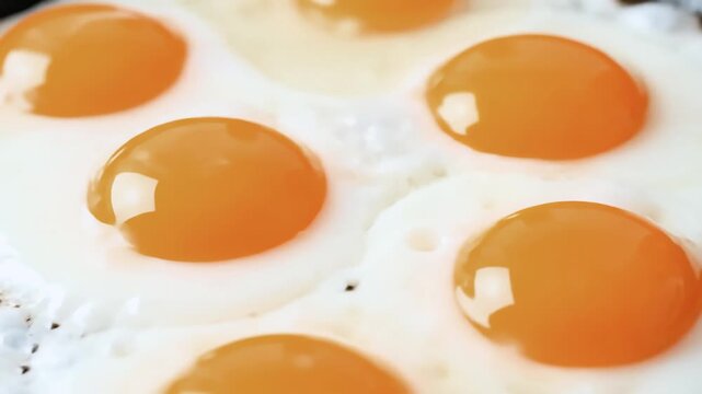 Close-up of fried eggs with vibrant orange yolks and white albumen.