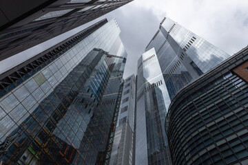 Modern glass skyscrapers reaching towards a cloudy sky
