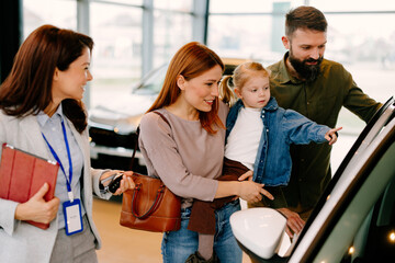 Obraz premium Happy family choosing new vehicle with sales consultant