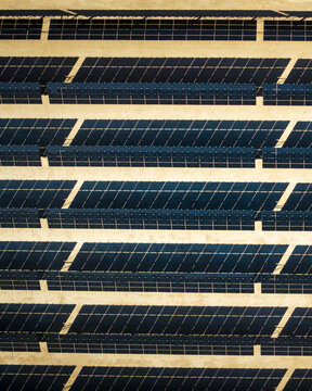Aerial view of rows of solar panels reflecting the sky, creating a striking contrast against the arid desert landscape, El Centro, California, United States.