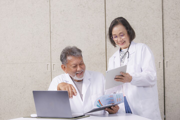 Obraz premium Two doctors in white coats are discussing medical charts in modern office. One is holding tablet, and other is looking at laptop, both smiling and engaged