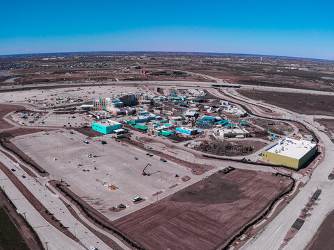 Aerial view of a vibrant theme park under construction, a symphony of blues and yellows against the raw earth, Frisco, Texas, United States.
