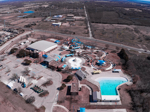 Aerial view of a waterpark with slides and pools nestled amidst a landscape of trees and buildings, Denton, Texas, United States.
