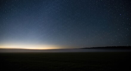 Fototapeta premium Starry-night-sky-during-twilight-over-serene-horizon-with-milky-way-galaxy-and-diffused-earthlight-reflection-on-mist-covered-landscape