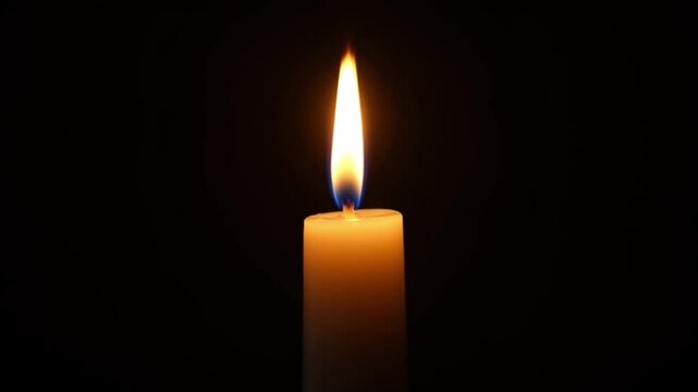 Burning candle flame isolated on black background symbol of hope warmth
