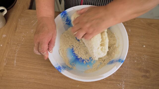 Pressing dough with hands in bowl. Unrecognizable person kneading mixture in container. Working mass into elastic form. Preparing dough for homemade bread