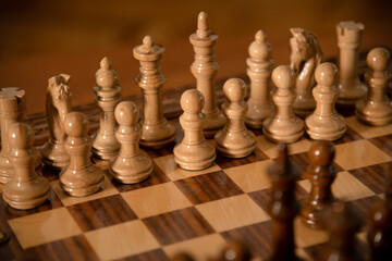 Wooden chess pieces set on a checkered board ready for a game