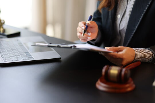 Female lawyer reviewing and signing a legal document while working on a case in her office.