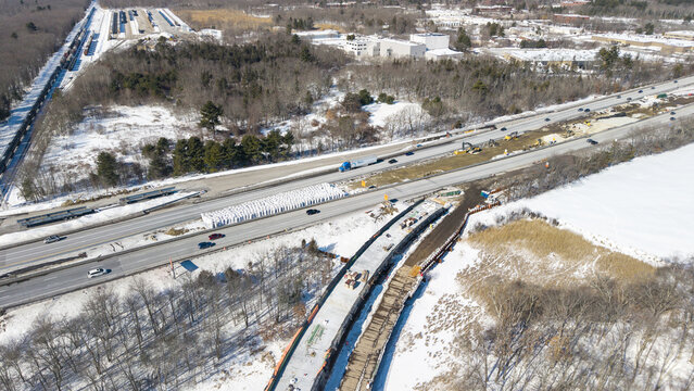 Aerial view of the contrast between the bare trees and the snow-covered ground alongside the highway with ongoing construction, Westborough, Massachusetts, United States.