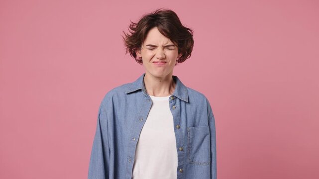 Young sad mad angry woman wear blue shirt white t-shirt casual clothes scream swear shout call out expressive gesticulating with hands isolated on plain pastel light pink background. Lifestyle concept