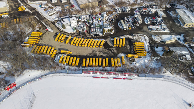 Aerial view of rows of bright yellow school buses contrasting against the stark white snow-covered ground, Providence, Rhode Island, United States.
