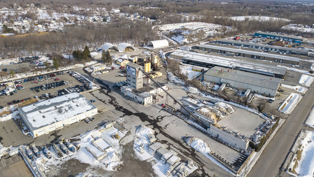 Aerial view of industrial structures contrasting against snowy patches and bare trees, a cold scene unfolds, Providence, Rhode Island, United States.