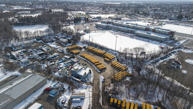 Aerial view of the school and yellow school buses parked on the snow-dusted ground creating an eye-catching contrast, Providence, Rhode Island, United States.
