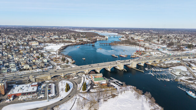 Aerial view of bridges gracefully arching over the Seekonk River as it reflects the clear sky, amidst a landscape dusted with snow, Providence, Rhode Island, United States.