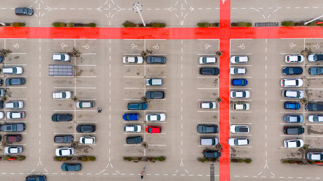 Aerial view of cars neatly aligned in a parking lot, with red pedestrian walkways cutting through the grey asphalt, Sremska Mitrovica, Vojvodina, Serbia.
