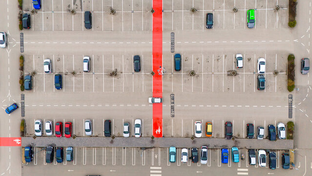 Aerial view of vehicles parked in a structured lot with bold red pedestrian walkways slicing through the orderly gray, Sremska Mitrovica, Vojvodina, Serbia.
