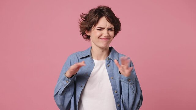Young woman wears blue shirt white t-shirt casual clothes look camera pointing fingers herself ask say who me no thanks i do not need it isolated on plain pastel light pink background studio portrait