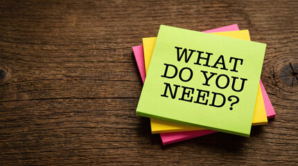 Colorful sticky notes on a wooden desk with the text what do you need for customer support concept.