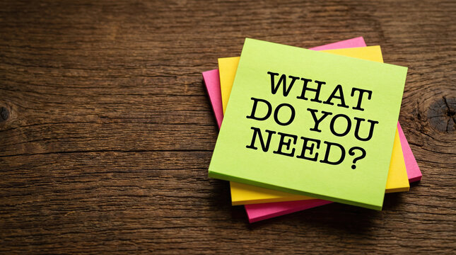 Colorful sticky notes on a wooden desk with the text what do you need for customer support concept.