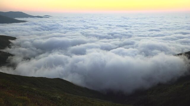 Rocky Mountains sunset above a sea of clouds, rugged range silhouette and glowing horizon. Dusk light over mist blanket, craggy peaks emerging, vast alpine vista across American West.