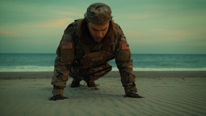 Naklejka premium American soldier doing push-ups on the beach for training near the ocean