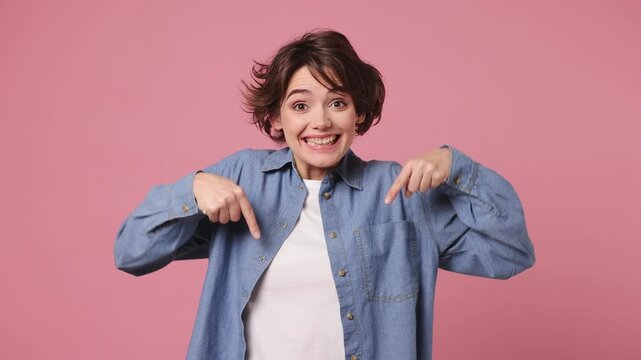 Young fun woman wears blue shirt white t-shirt casual clothes pointing indicate index finger down on workspace area copy space mock up isolated on plain pastel light pink background. Lifestyle concept