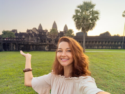 Happy Woman Taking Selfie and Pointing at Angkor Wat Temple in Cambodia