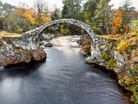 Alte Steinbr&uuml;cke in Carrbridge, Schottland mit romantischem Br&uuml;ckenbogen und flie&szlig;endem Flu&szlig; in Langzeitbelichtung