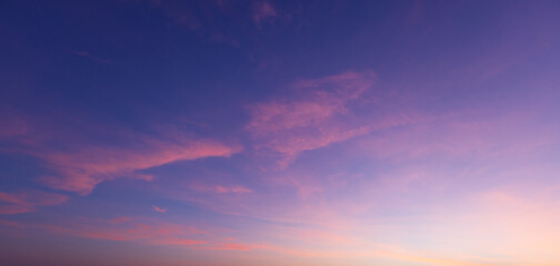 Obraz premium Beautiful sunset sky with orange and blue gradient clouds background,A stunning panoramic view of the twilight sky during sunset, featuring a vibrant gradient of deep blue, purple, and golden orange 