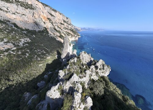 Picturesque rocky coast, cliffs with L'Aguglia pinnacle, blue sea and Cala Goloritz&eacute; beach, aerial view, Golfo di Orosei, Baunei, Sardinia, Italy