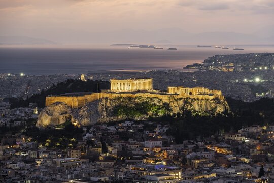 View over the sea of houses of Athens, illuminated Parthenon temple on the Acropolis, from Mount Lycabettus, Athens, Greece