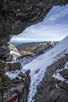 View through rock hole, Fensterl, mountain landscape with snow in autumn, hiking trail to Ammergauer Hochplatte, Ammergau Alps, Bavaria, Germany