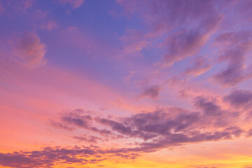 Obraz premium Beautiful sunset sky with orange and blue gradient clouds background,A stunning panoramic view of the twilight sky during sunset, featuring a vibrant gradient of deep blue, purple, and golden orange 