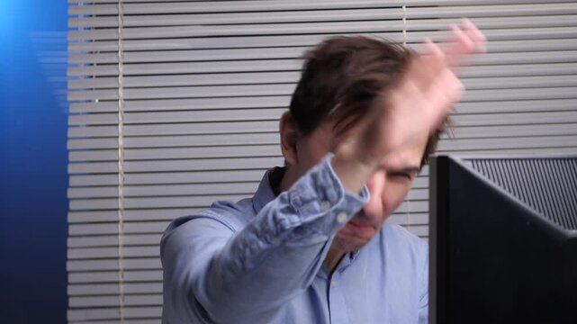 Frustrated businessman angrily gesturing at a malfunctioning monitor in a modern office, expressing stress, tech rage and annoyance over computer or internet errors during work