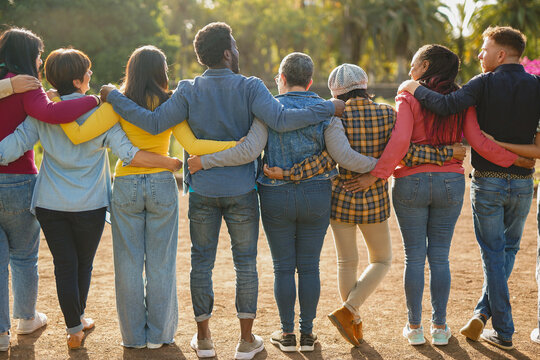 Group of multiracial people hugging each other at city park - Back view of multi generational community - Humanity, social inclusion and diversity concept
